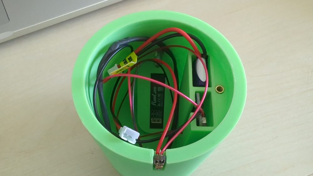 Inside the green module: the RunCam Thumb camera, a purple LiPo and the power switch