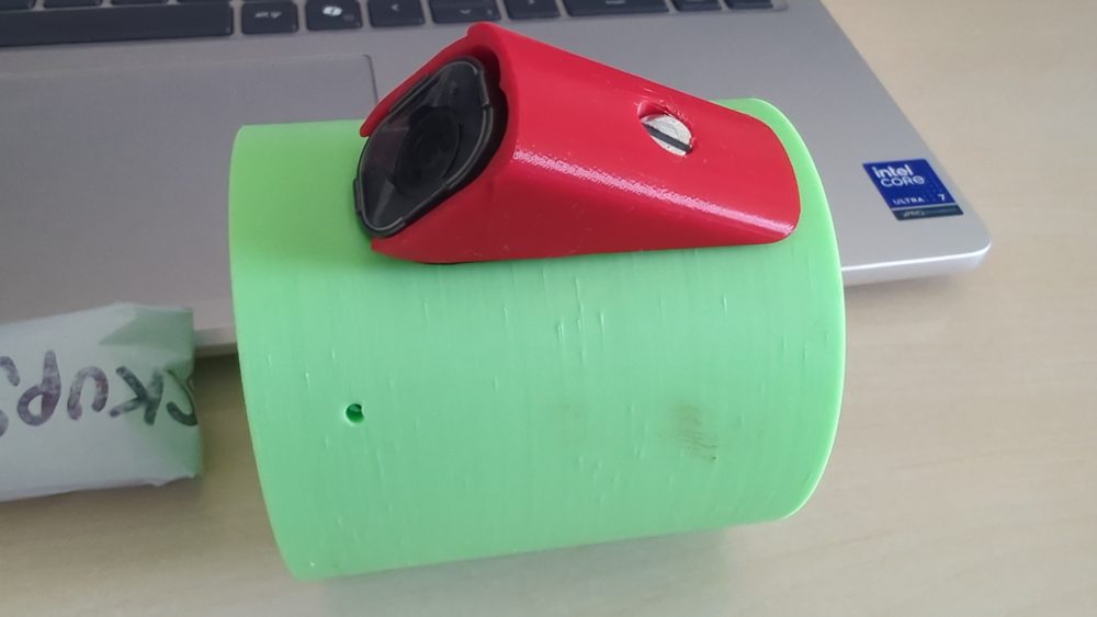 The 3D-printed rocket module: a green cylindrical housing with a red camera enclosure holding the RunCam lens